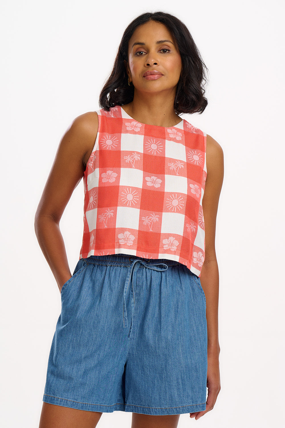A model wearing an off-white and coral tropical gingham sleeveless top with a round neckline and keyhole back.