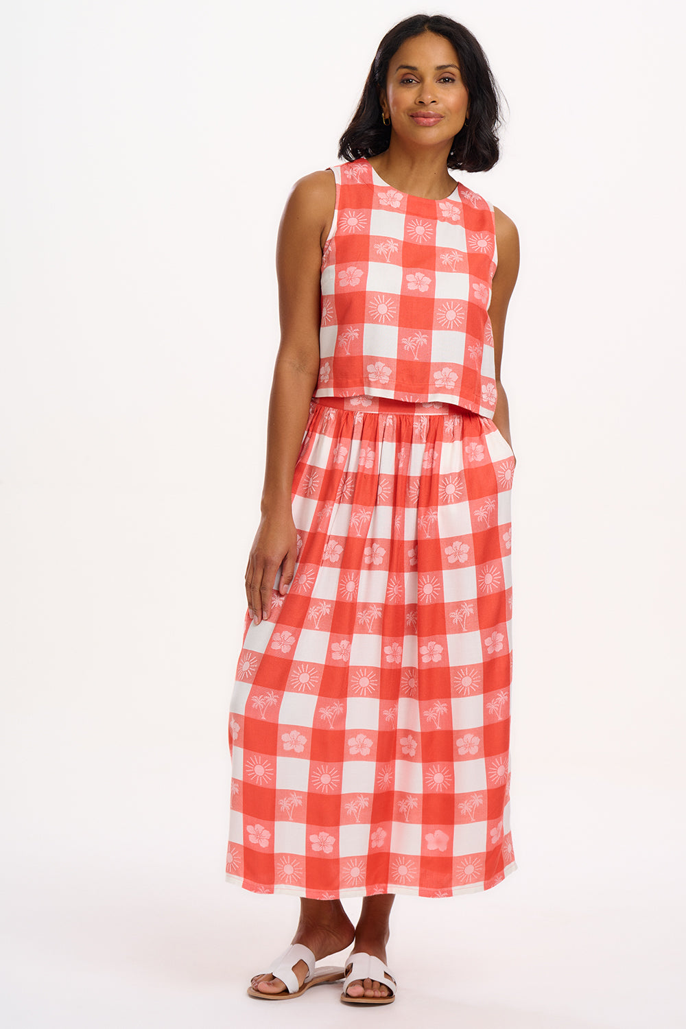 A model wearing an off-white and coral gingham sleeveless top with a round neckline and an angular keyhole back.