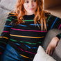 Sugarhill brighton model wearing a colorful striped sweater sitting on a couch.