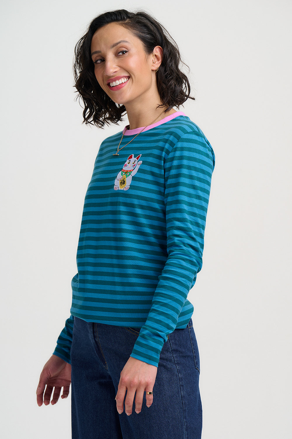Woman wearing a blue striped sweater with a cat design on a white background