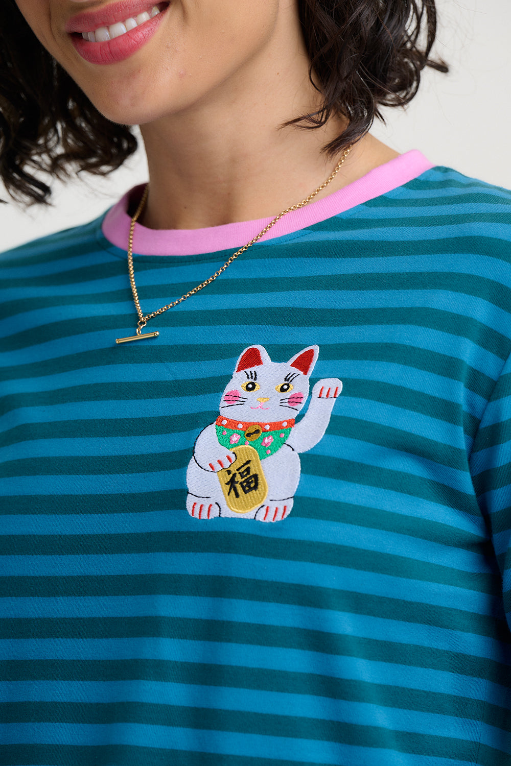 Person wearing a blue striped shirt with a cartoon cat design and pink collar.