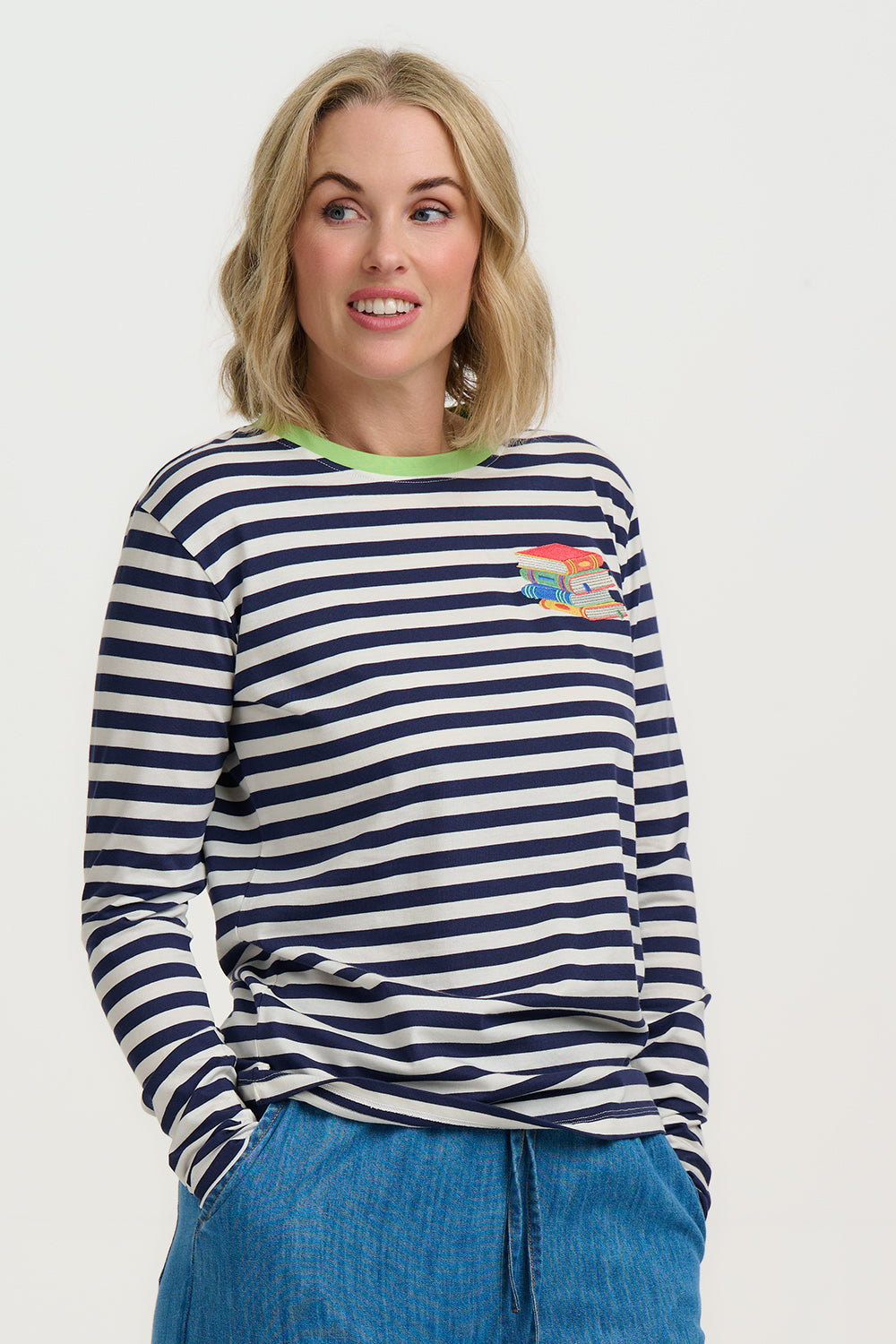 Woman wearing a navy and white striped sweater with a colorful patch on a plain background