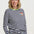 Woman wearing a navy and white striped sweater with a colorful patch on a plain background