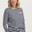 Woman wearing a navy and white striped sweater with a colorful patch on a plain background