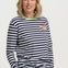 Woman wearing a navy and white striped sweater with a colorful patch on a plain background