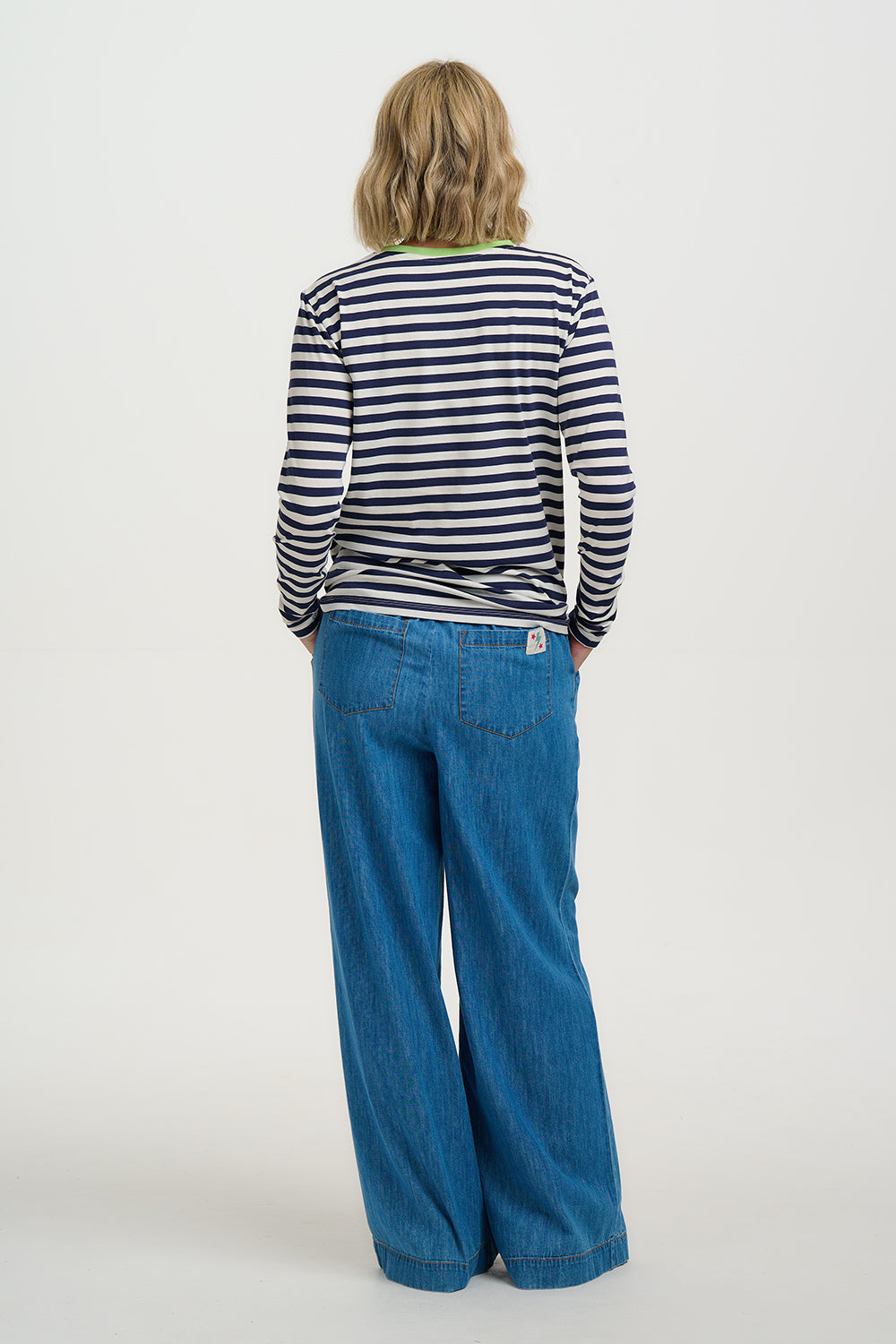 Person wearing a striped shirt and blue jeans on a white background