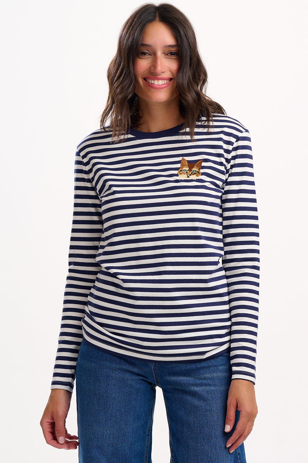 Woman wearing a navy and white striped long-sleeve shirt with a small logo, standing against a plain background.