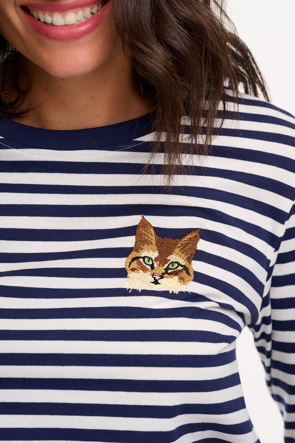 Navy and white striped shirt with a cat face design on a person wearing it.
