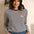 Woman wearing a striped sweater with a cat patch in a casual setting