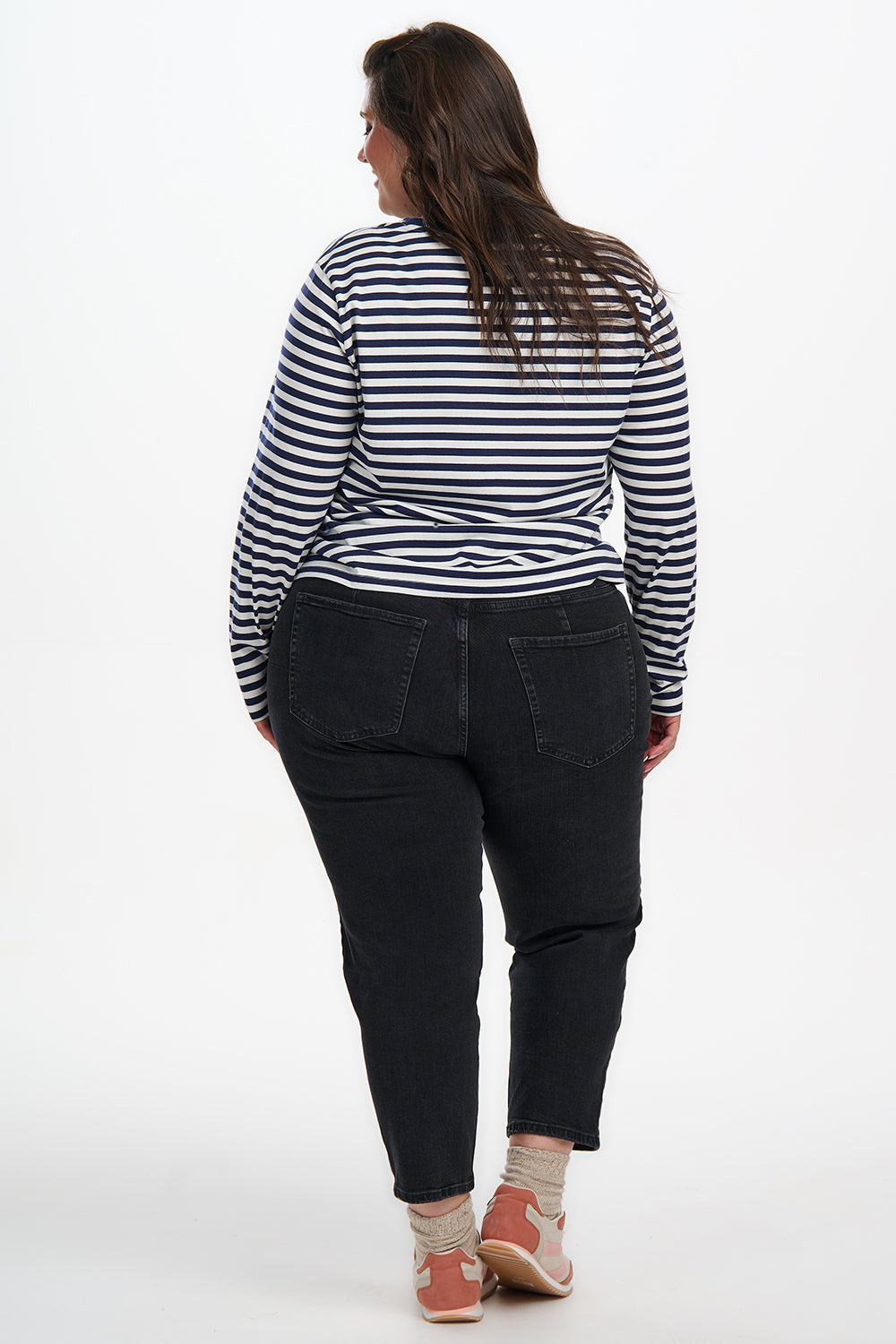 Person wearing a black and white striped shirt and dark pants on a white background