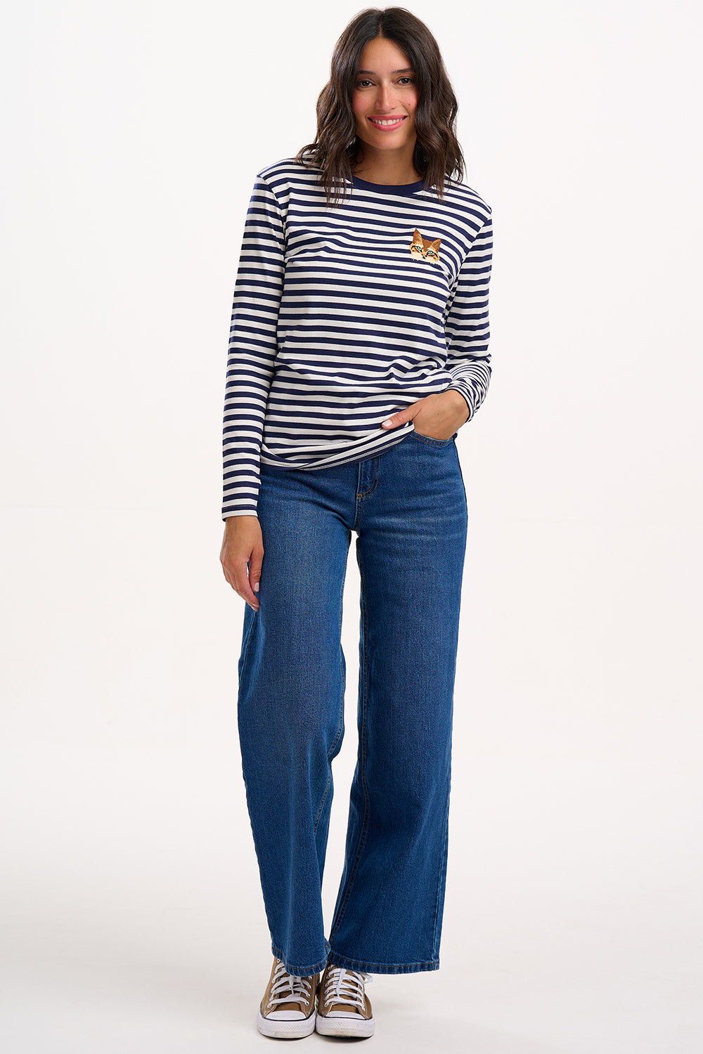 Woman wearing a striped long-sleeve shirt and blue jeans on a white background