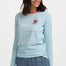 Woman wearing a blue and white striped long-sleeve shirt with a small design on a plain background