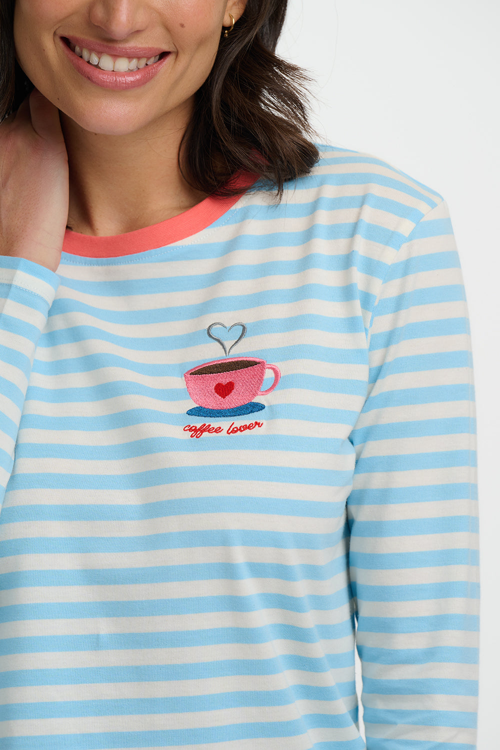 Woman wearing a blue and white striped shirt with a coffee-themed design.