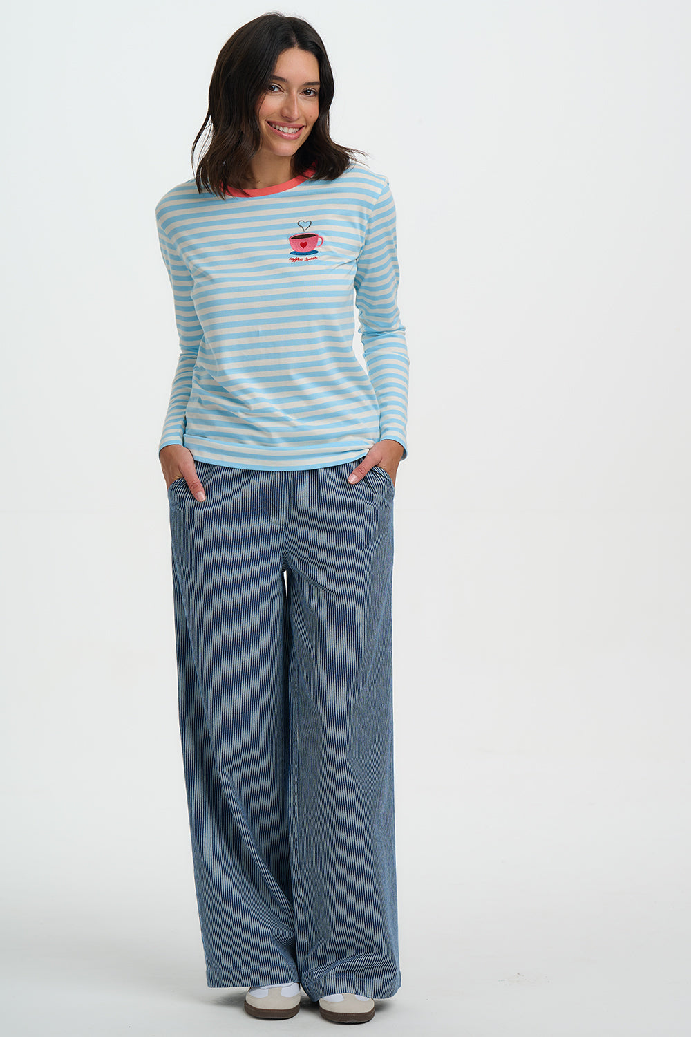Woman wearing a striped long-sleeve shirt and wide-leg jeans on a white background