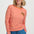 Woman wearing an orange and pink striped long-sleeve shirt with a small logo on a white background