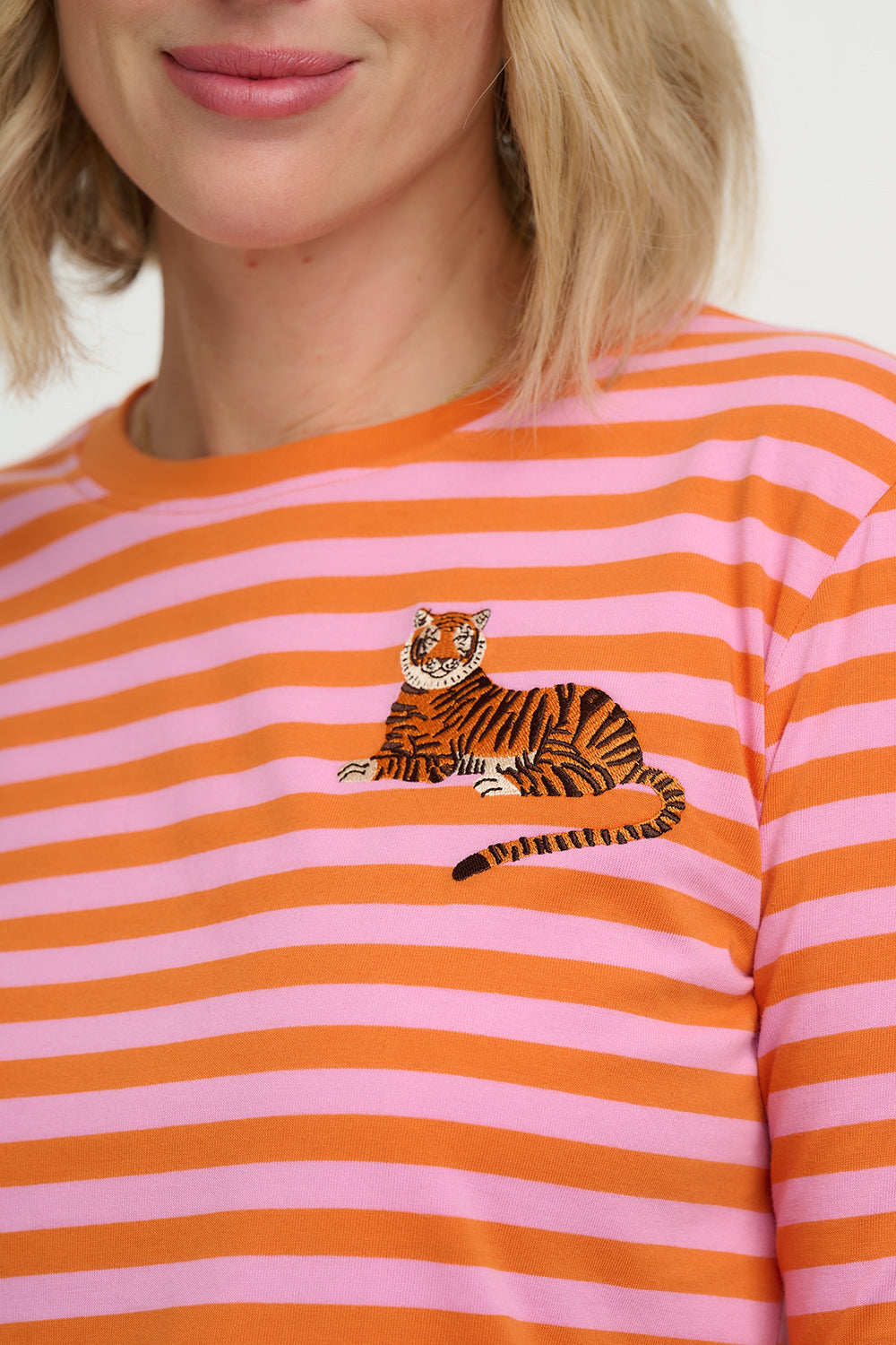 Person wearing a pink and orange striped shirt with a tiger design.