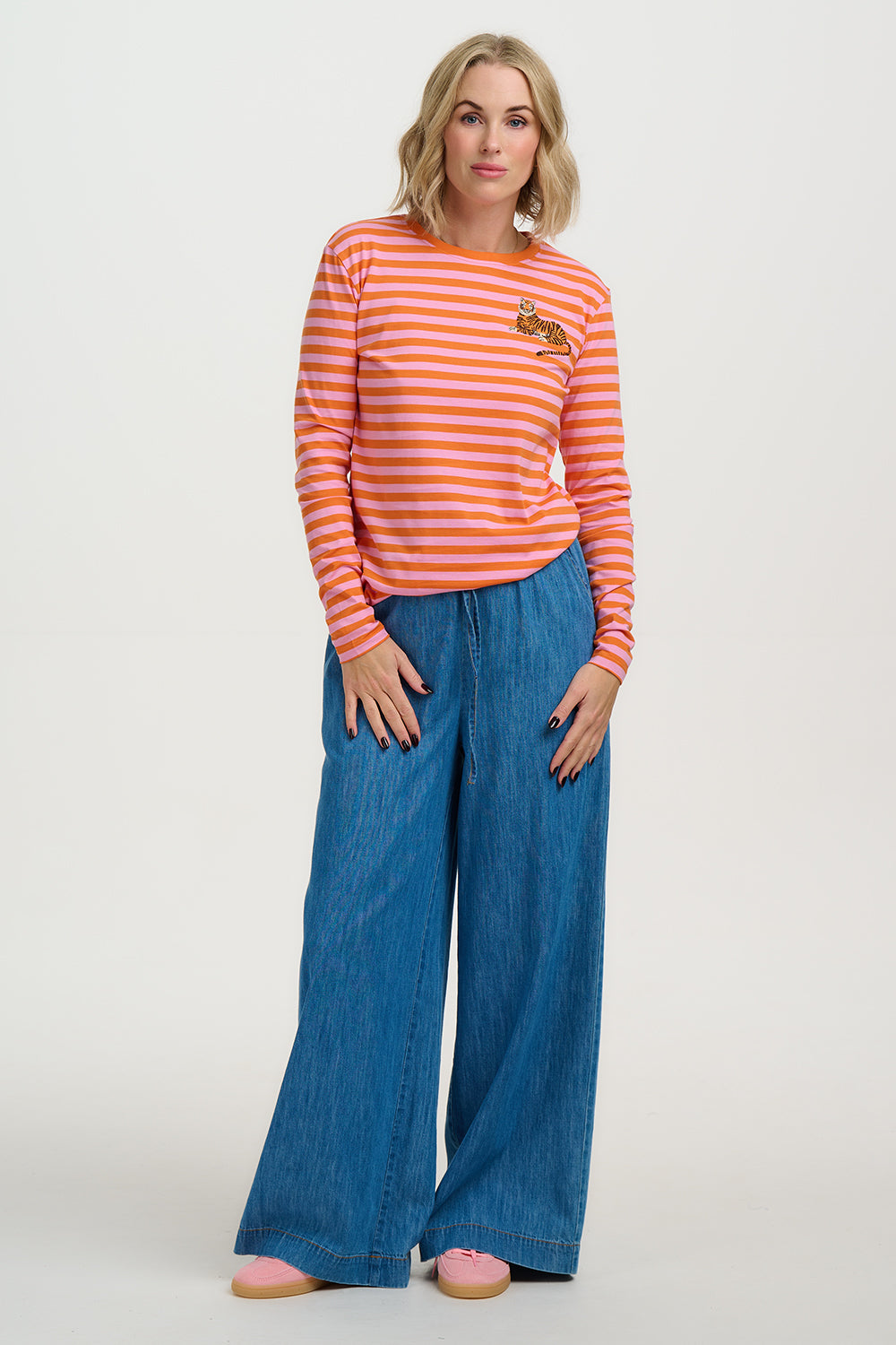 Woman wearing a striped shirt and wide-leg jeans on a white background