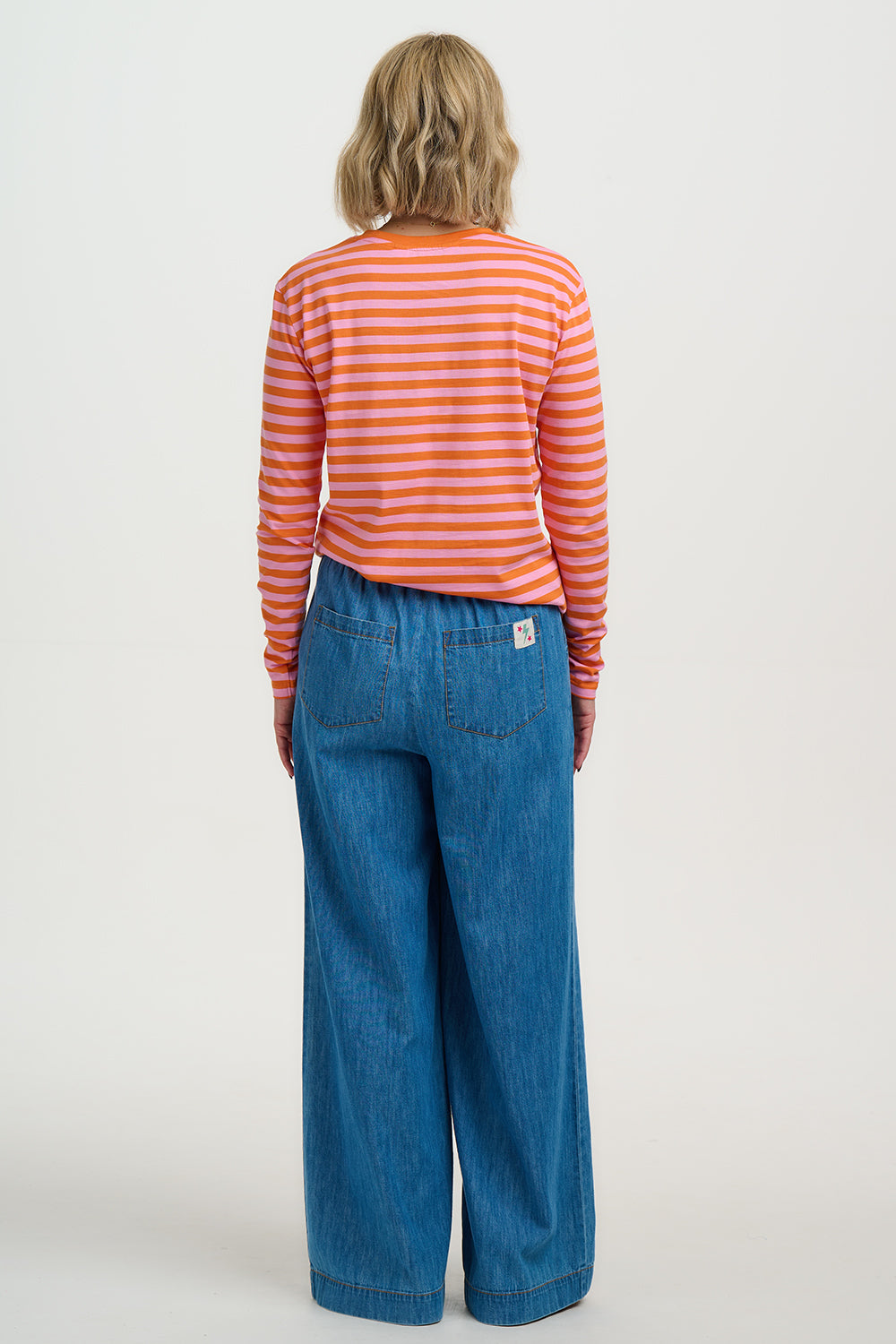 Person wearing a striped shirt and blue jeans on a white background