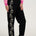 Person wearing black pants with floral embroidery and a pink sweatshirt on a white background