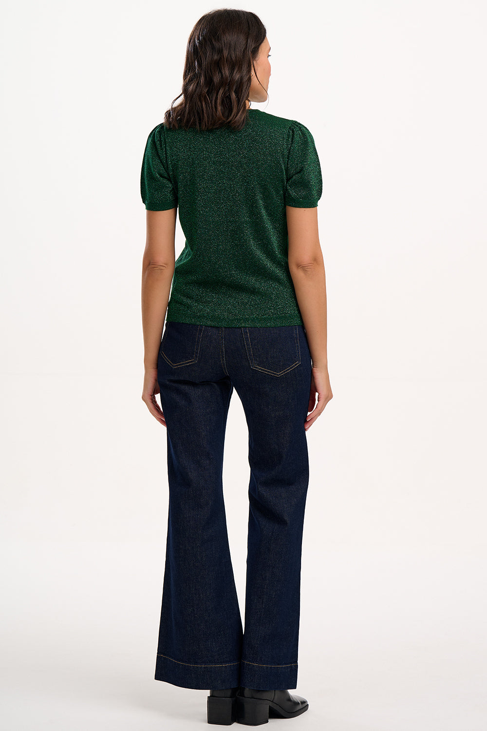 Person wearing a green top and dark blue jeans on a white background