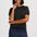 A woman modeling a short-sleeve dark gray knit top and a dark blue denim mini skirt with a scalloped hem, against a light gray studio background.