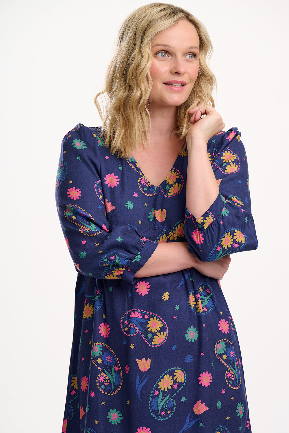 Woman wearing a blue dress with colorful floral patterns on a white background