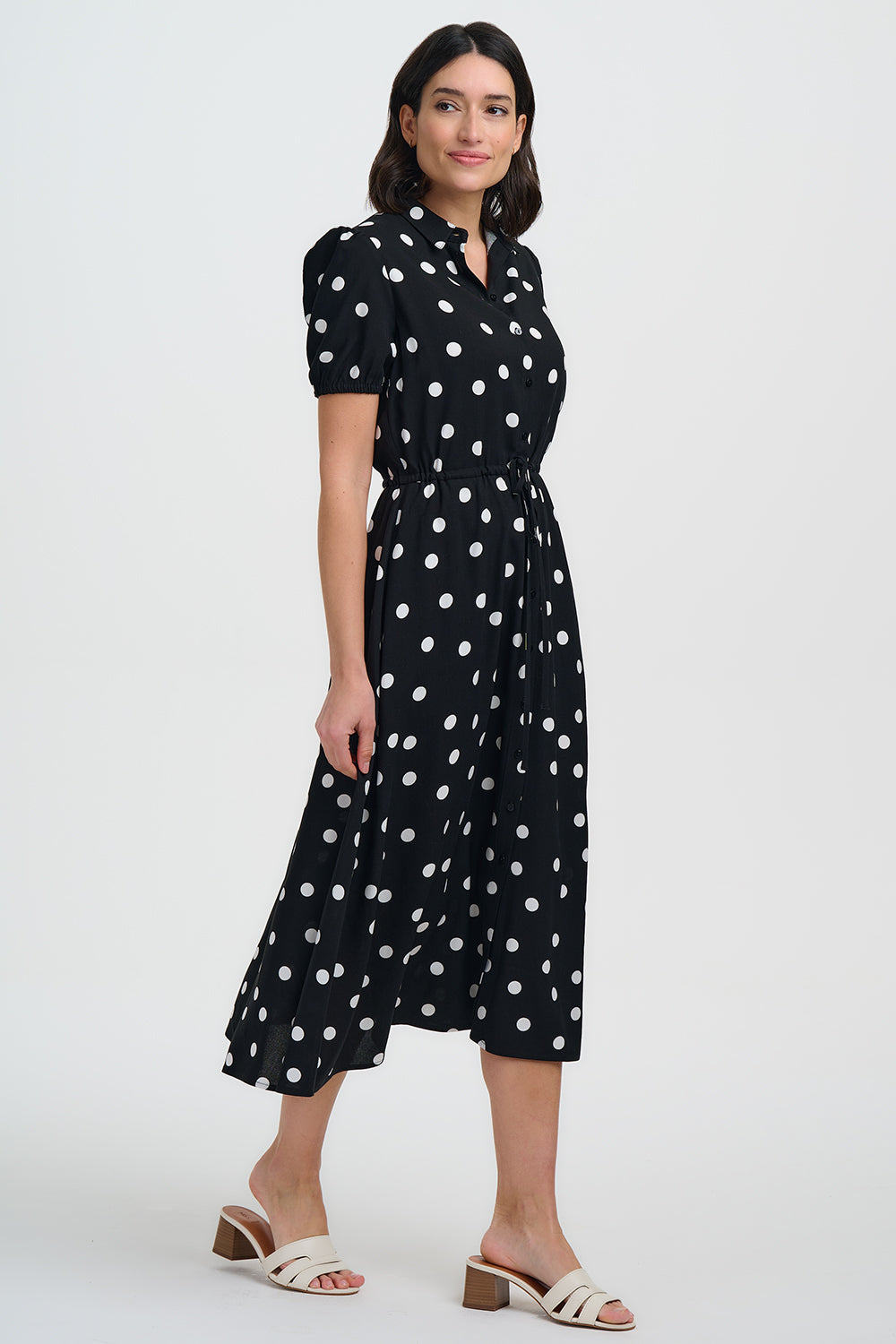 Woman wearing a black dress with white polka dots on a white background