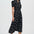 Woman wearing a black dress with white polka dots on a white background