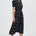Woman wearing a black dress with white polka dots on a white background