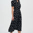 Woman wearing a black dress with white polka dots on a white background