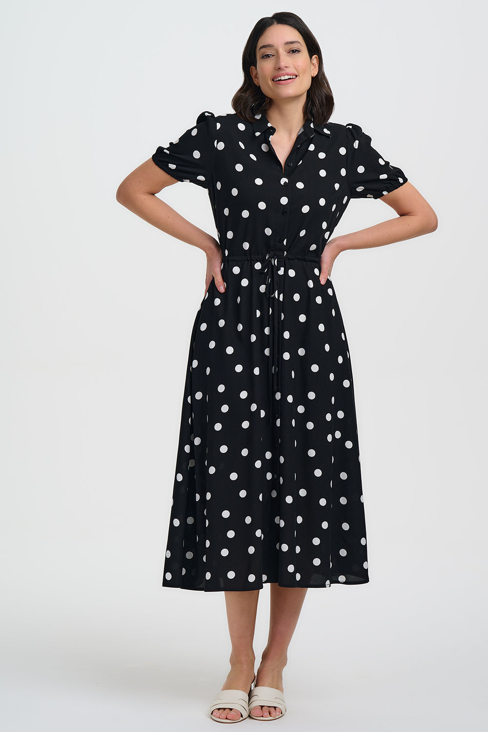 Woman wearing a black dress with white polka dots on a white background