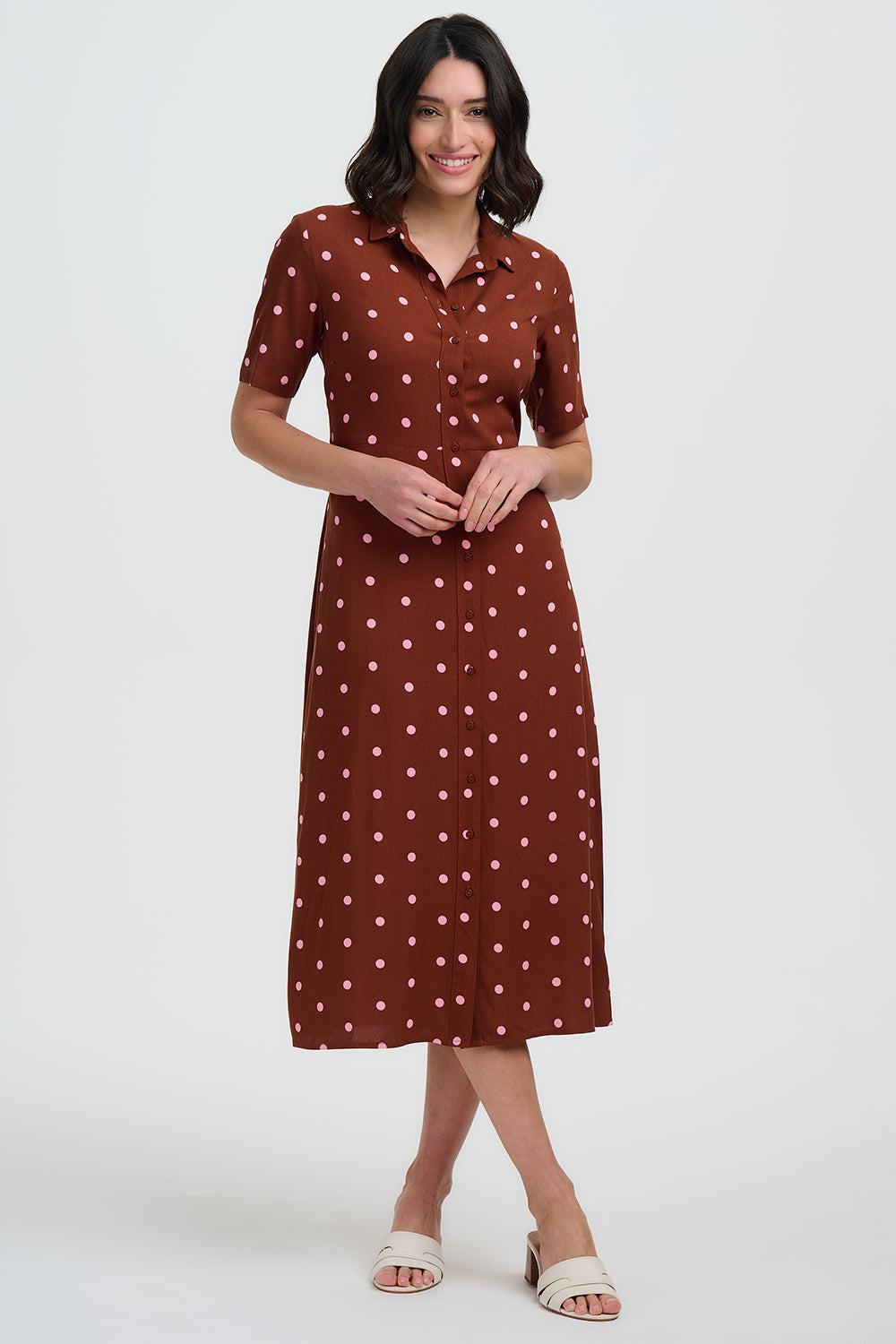 Woman wearing a brown dress with white polka dots on a white background