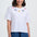 Woman wearing a white t-shirt with colorful floral embroidery on a plain background