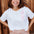 Woman wearing a white t-shirt with red heart pattern and leopard print pants standing against a wooden background