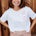 Woman wearing a white t-shirt with red heart pattern and leopard print pants standing against a wooden background