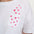 White t-shirt with pink heart patterns on a plain background