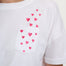 White t-shirt with pink heart patterns on a plain background