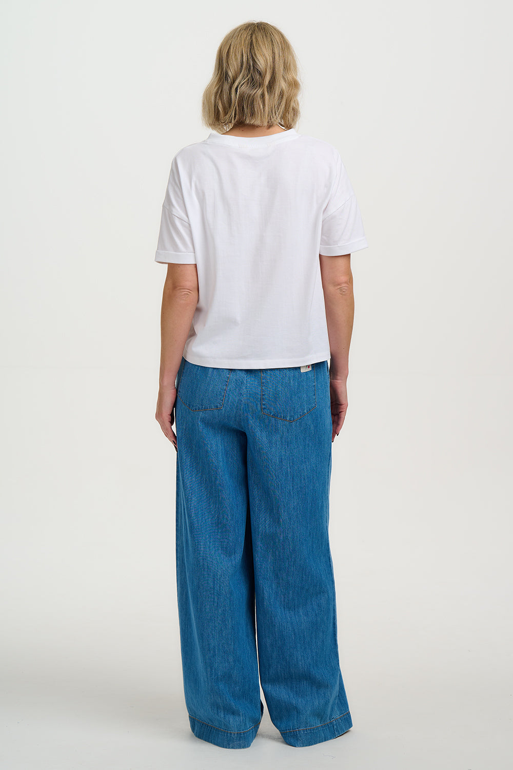 Person wearing a white t-shirt and blue jeans on a white background