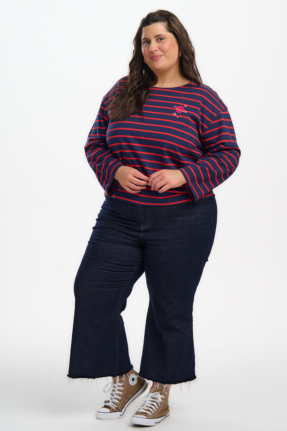 Woman wearing a striped sweater and dark pants on a white background