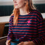 Sugarhill brighton model wearing a navy and red striped sweater with a pink planet design, holding a blue mug.
