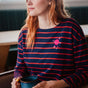 Sugarhill brighton model wearing a navy and red striped sweater with a pink planet design, holding a blue mug.