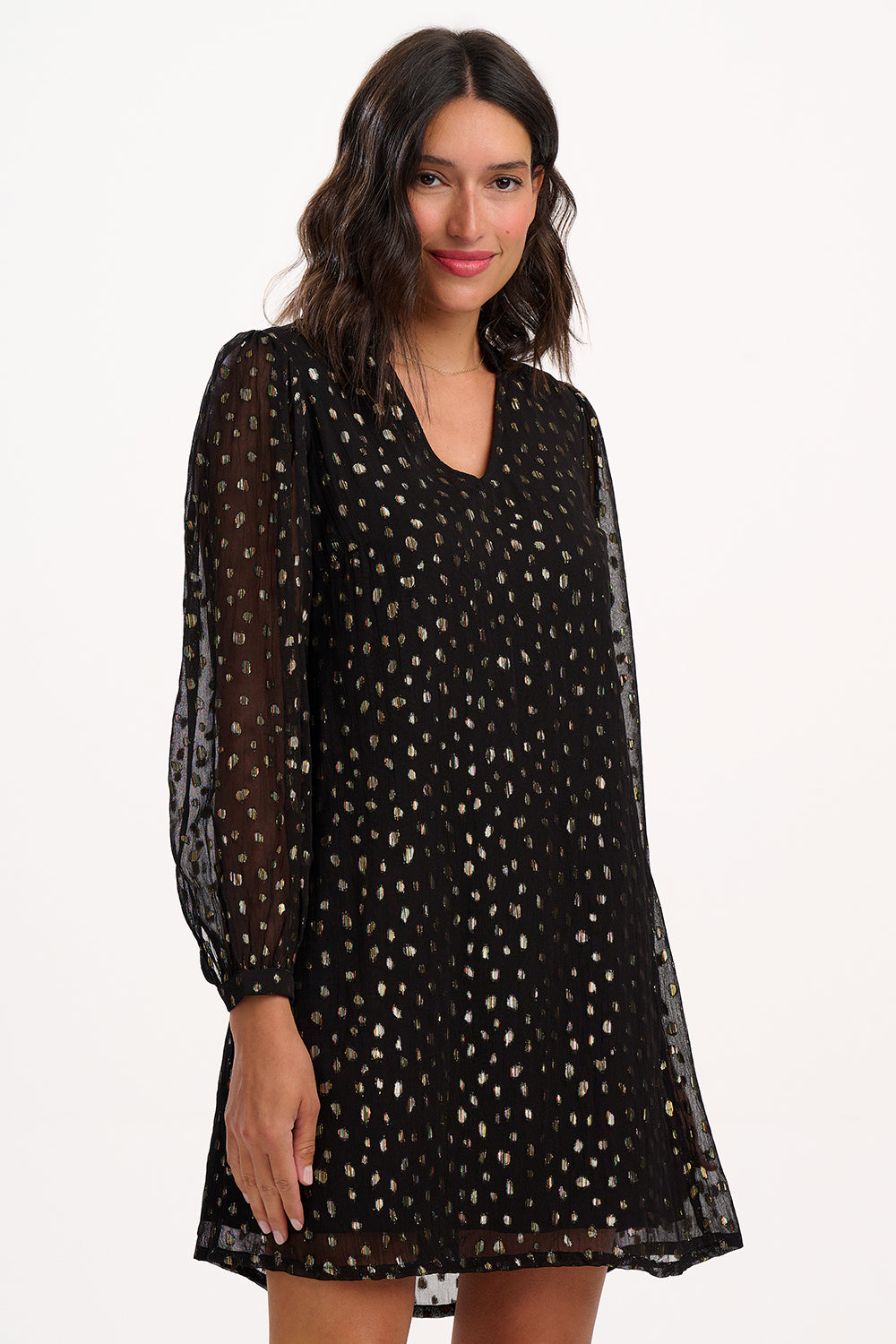 Woman wearing a black dress with gold polka dots on a white background