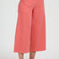 Person wearing coral wide-leg pants on a white background