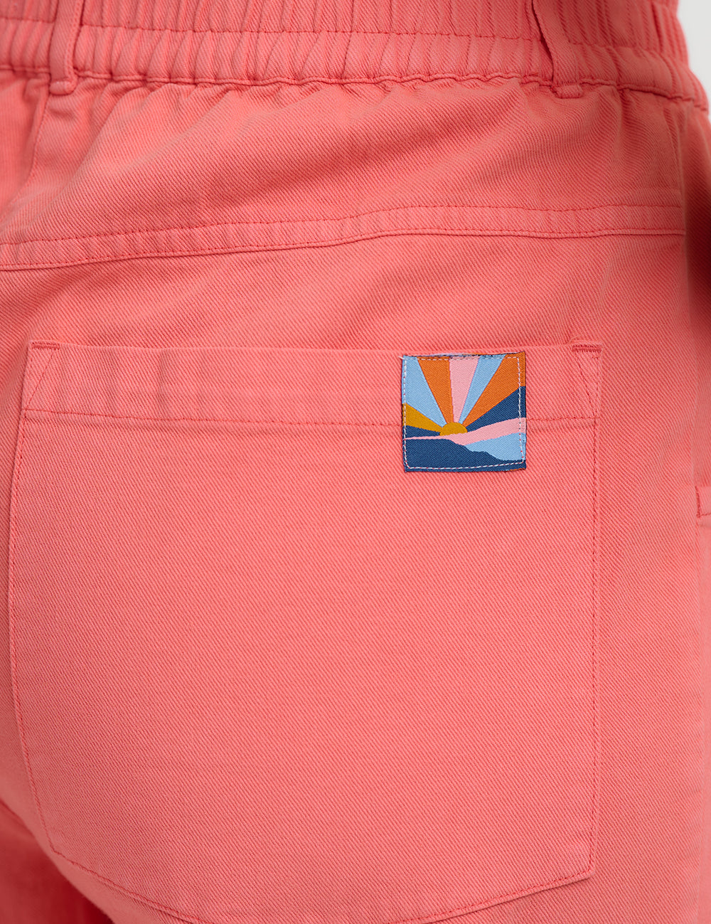 Close-up of pink pants with a colorful label on the pocket.