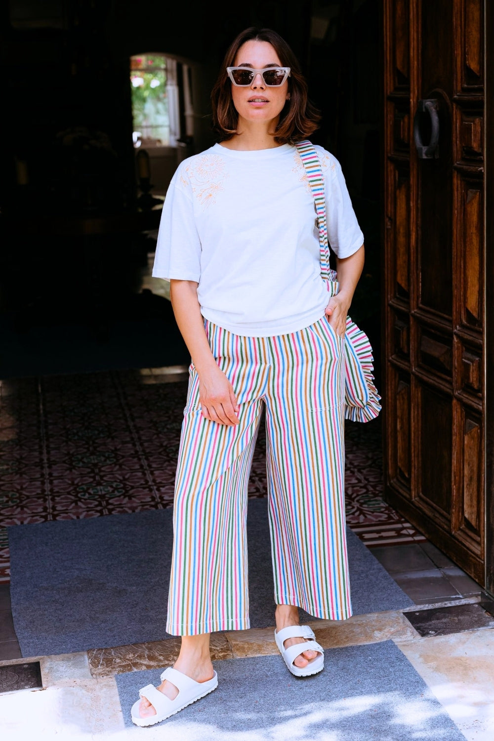 Woman wearing awhite tshirt and colorful striped pants