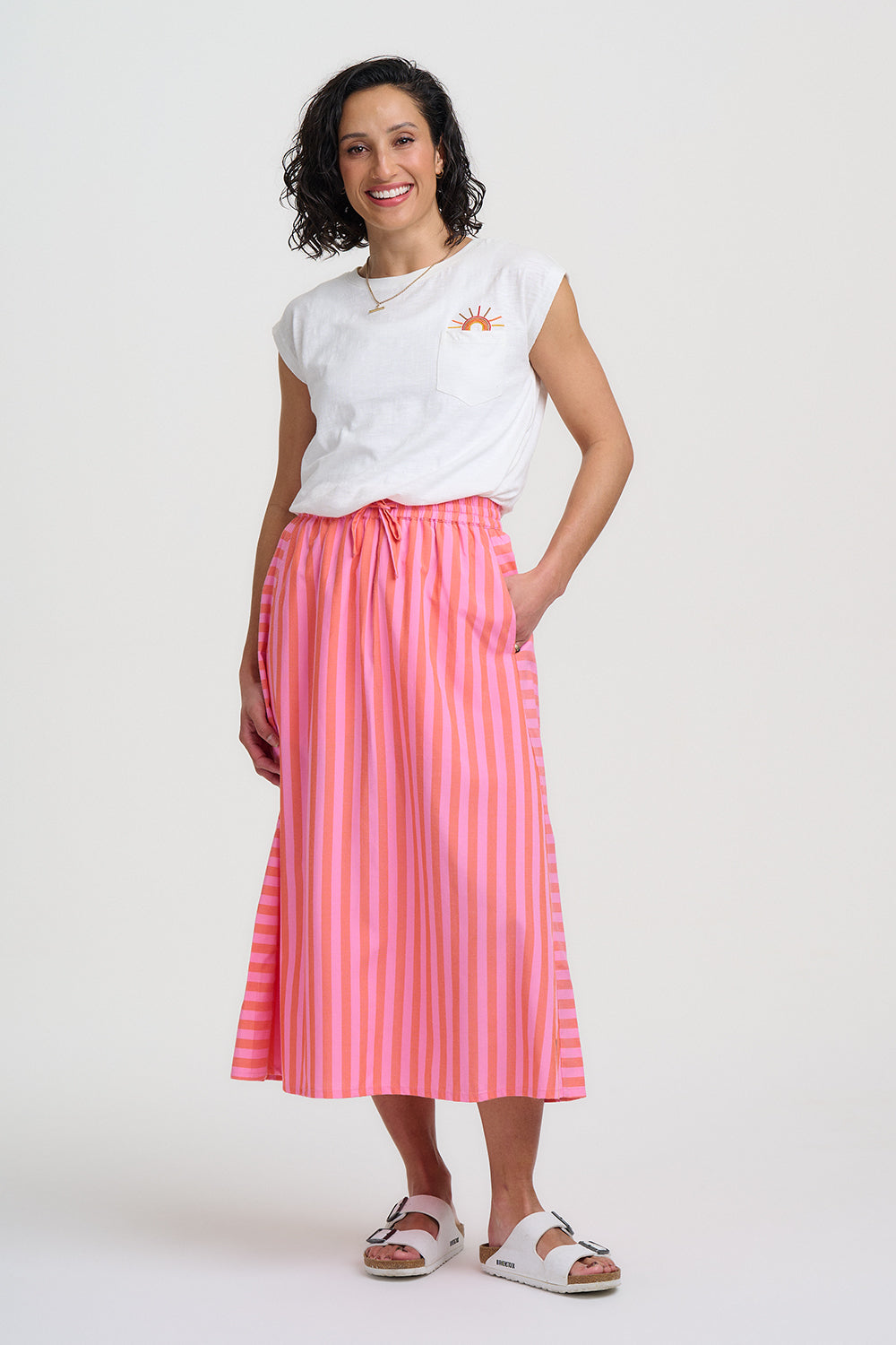 Woman wearing a white t-shirt and pink striped skirt on a white background