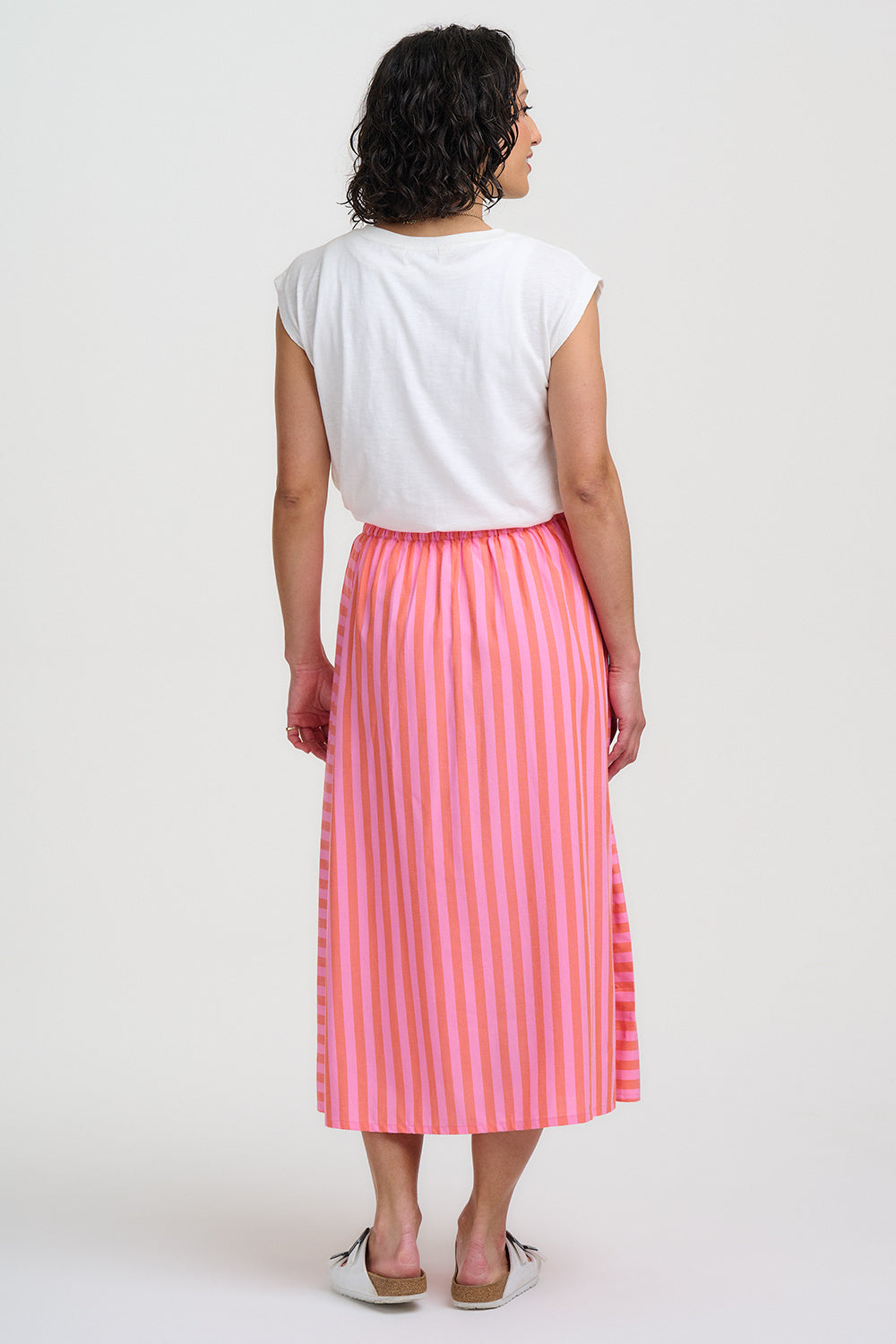 Woman wearing a white top and pink striped skirt on a white background
