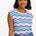 A woman smiling and wearing a sleeveless round neck t-shirt with a multicolored geometric pattern in shades of pink, green, and blue.
