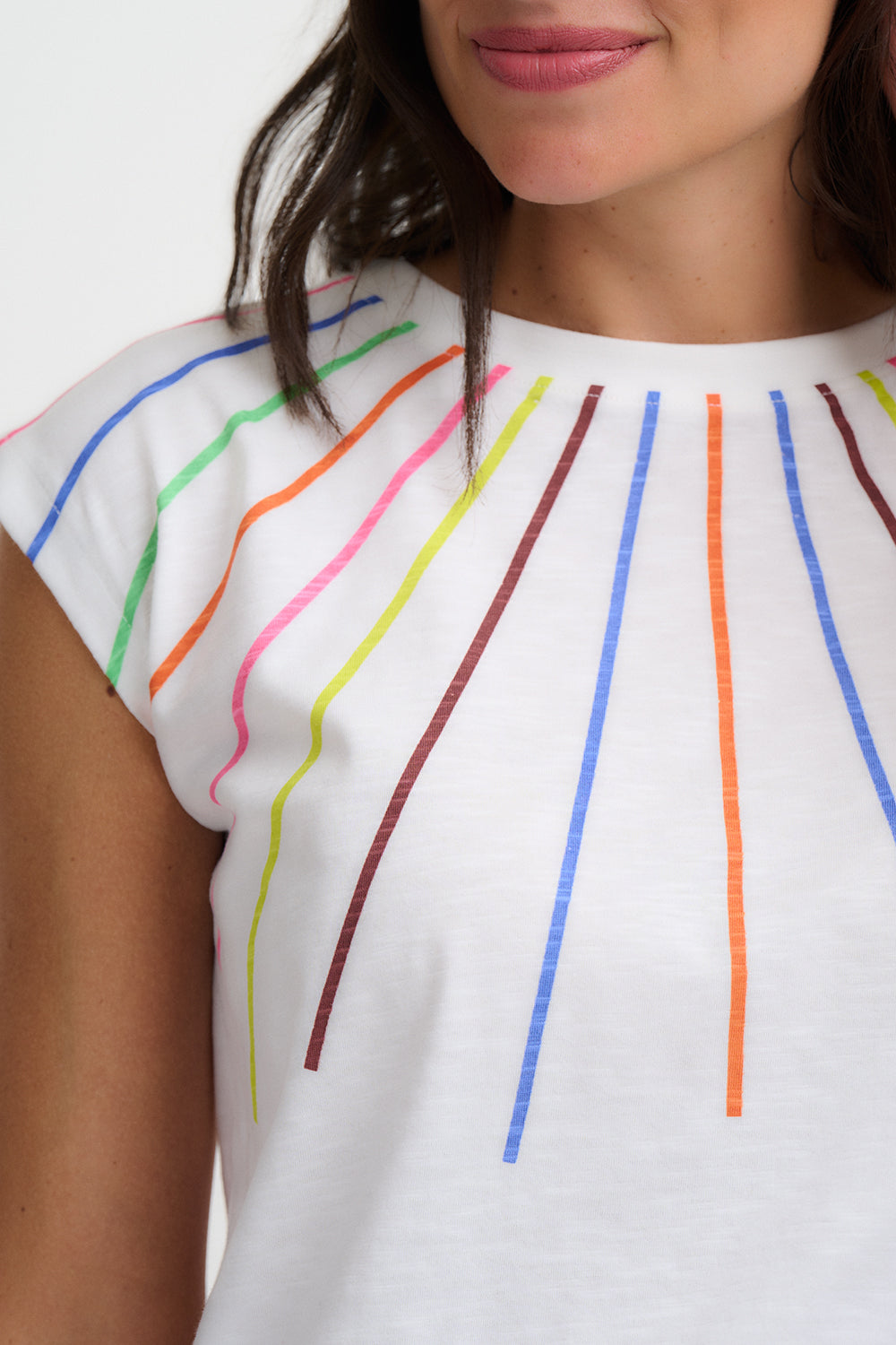 White top with colorful vertical lines worn by a person on a white background