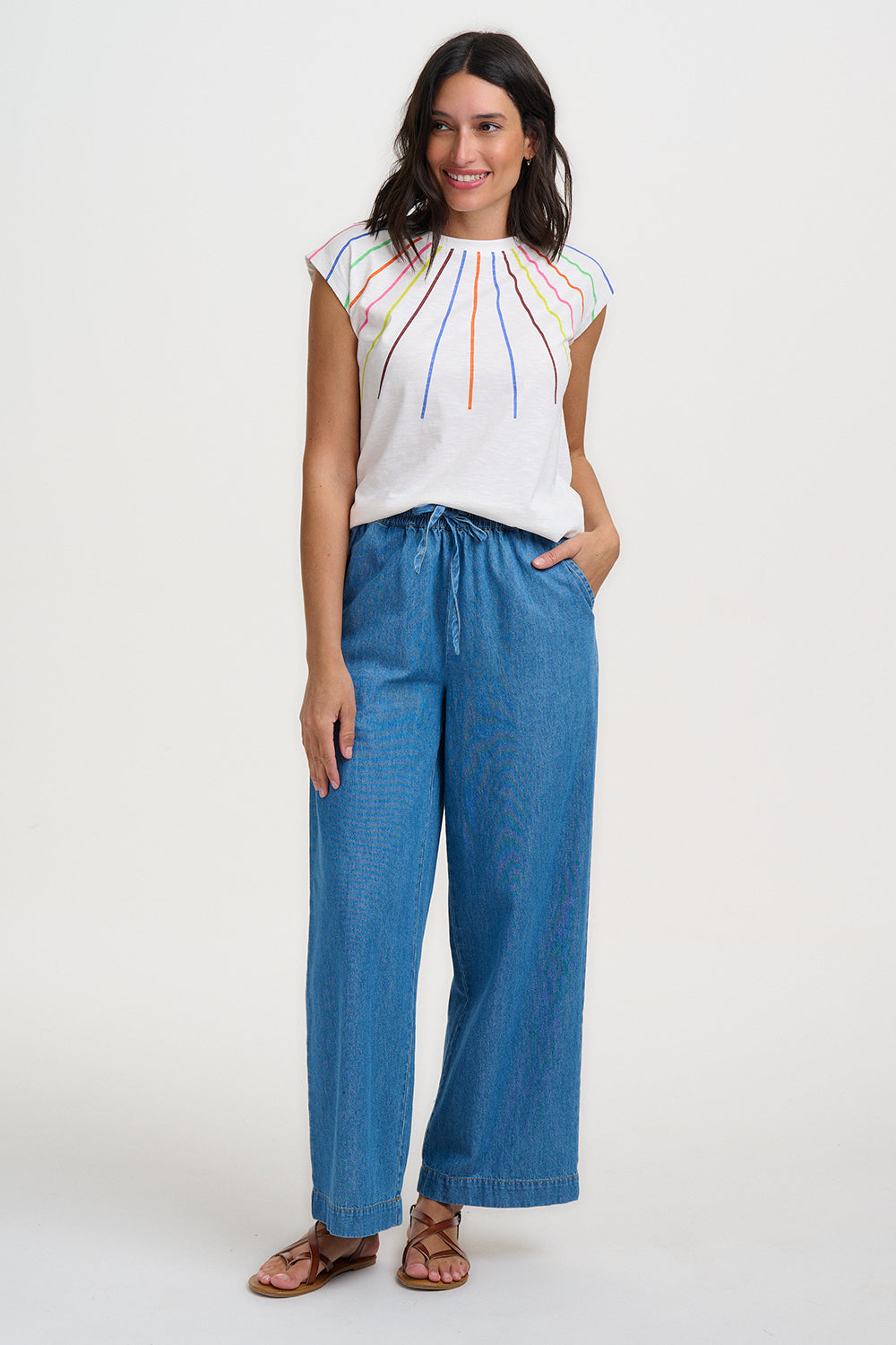 Woman wearing a colorful top and blue pants on a white background